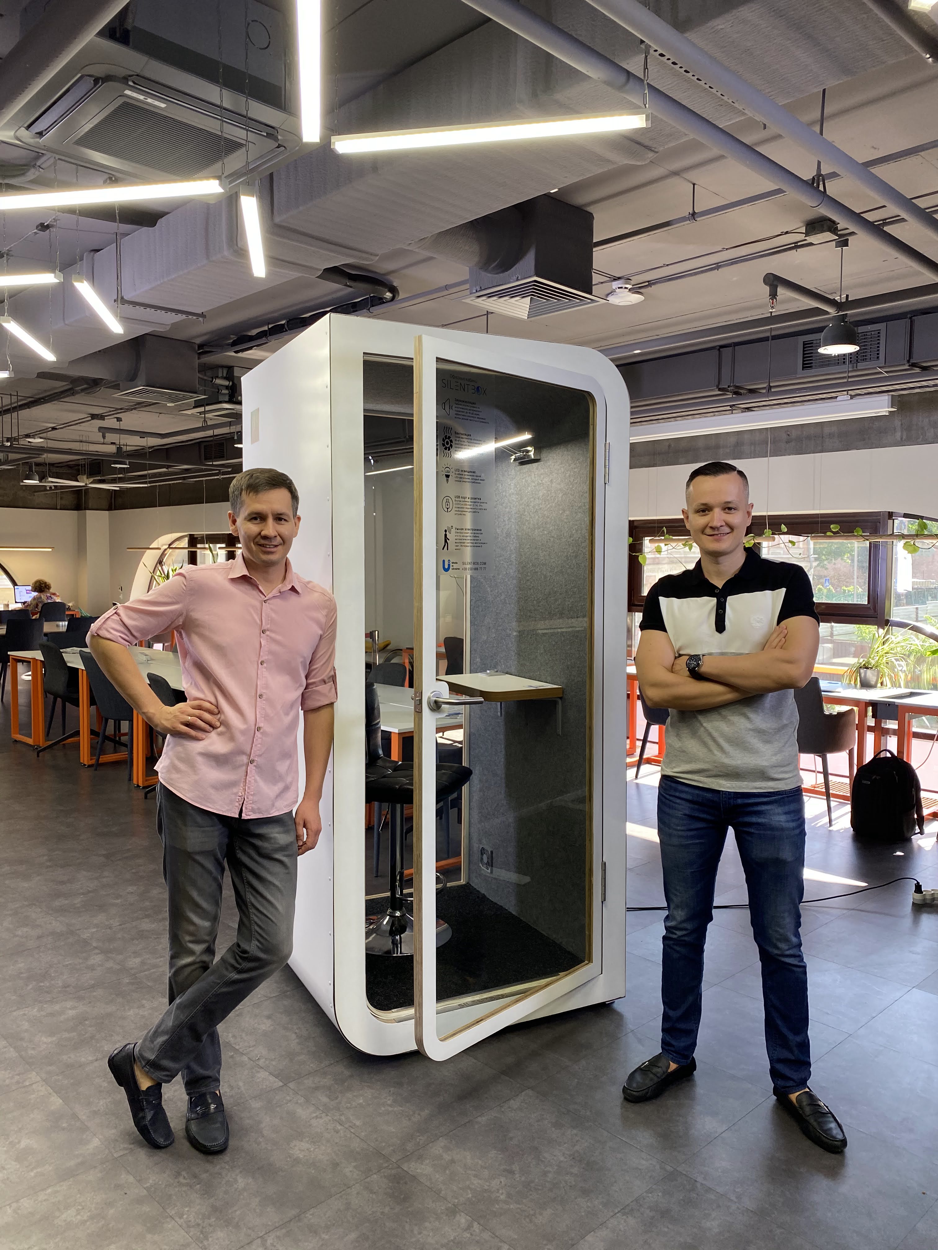 Sviatoslav and Yevhen Serbin, founders of Silentbox, next to an acoustic booth in an office