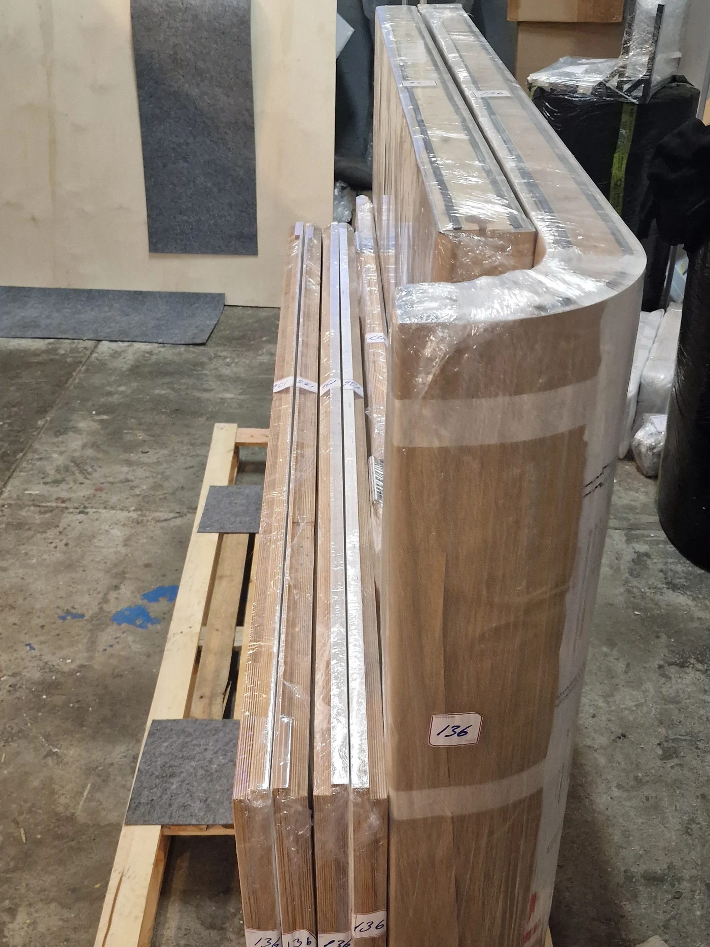 Silentbox acoustic booth sections in factory storage, wrapped in protective film with order numbers