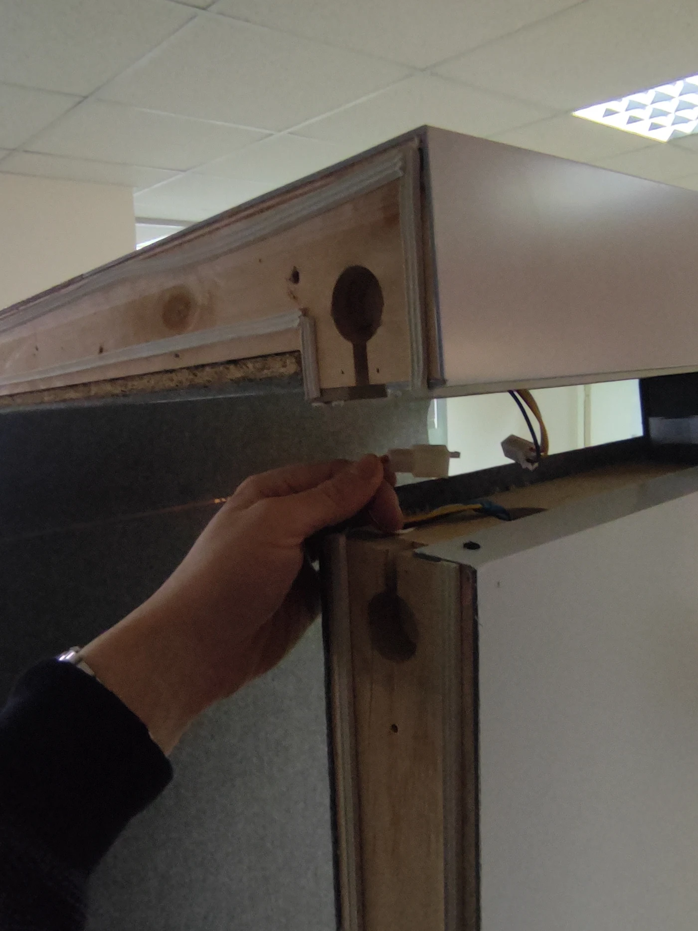 An installer wiring the ceiling module of a Silentbox booth — motion sensor and power supply visible