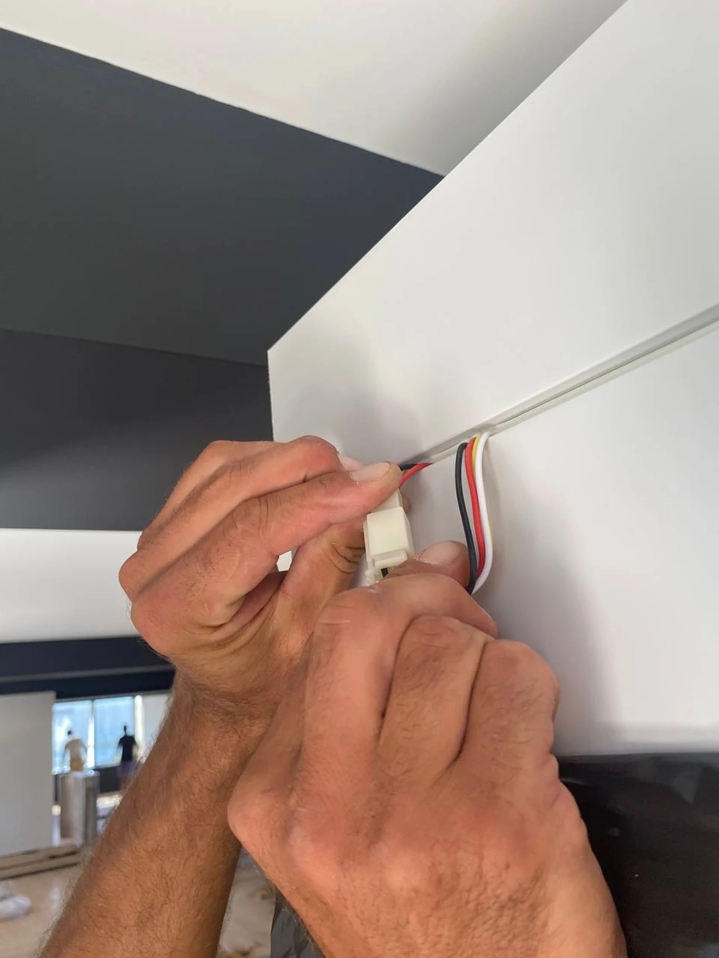 An installer connecting a wiring connector under the ceiling panel of a Silentbox booth