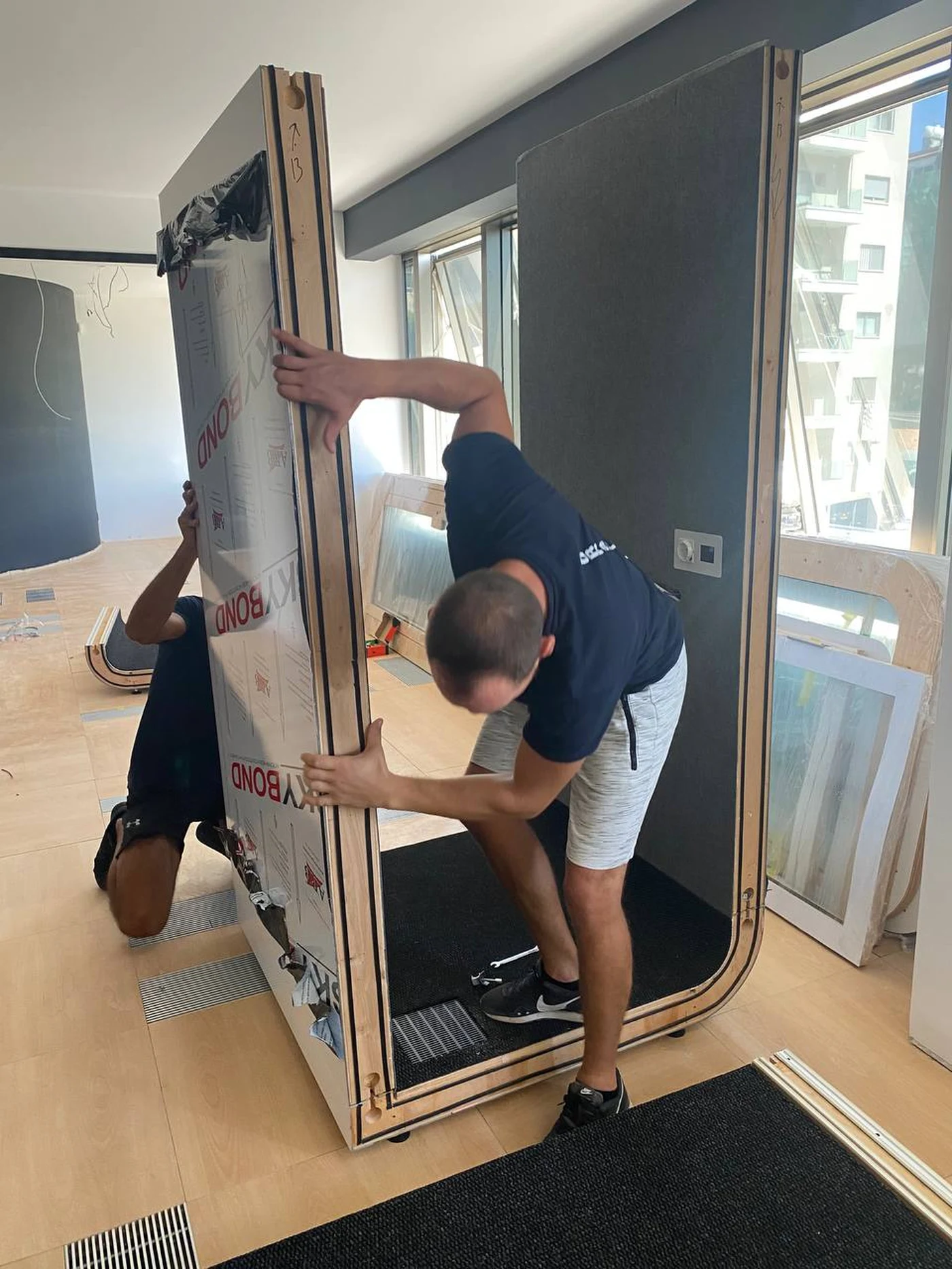 An installer fitting a side panel of the Silentbox booth still in its SKYBOND factory film